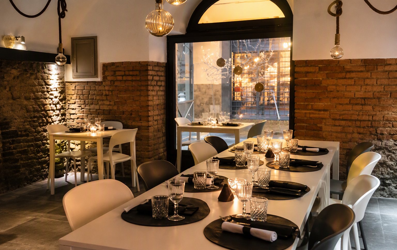 La sala con i tavoli bianchi e il muro in mattoni